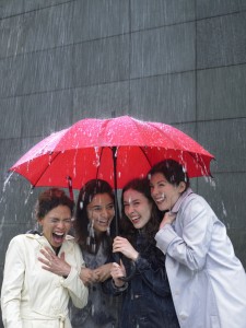 Four women sharing umbrella in the rain
